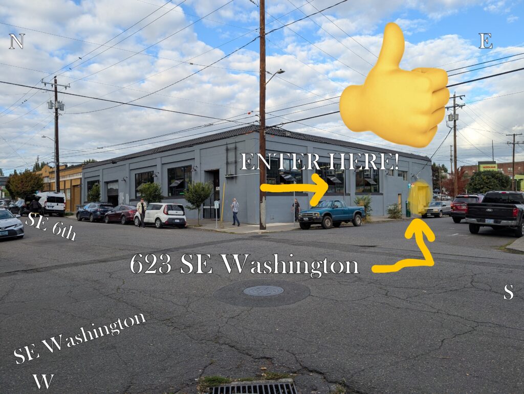 Daytime photo from kitty corner across the interestcion of SE 6th and Washington showing the non-descript grey building where the nightmarket will be. A large thumbs up emoji, and arrows point to the entrance highlighted in yellow toward the back (east end) of the building on SE Washington. Text labels show the street names, and N, E, S, W directionals. So it's clear where to go.